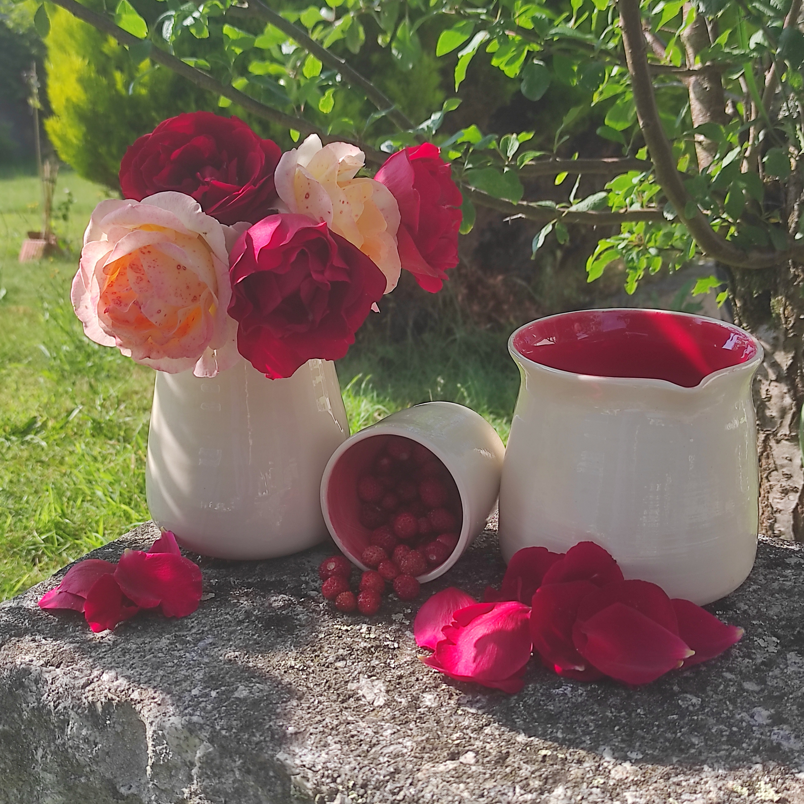 Gobelet, pichet et vase rouges avec des fruits et des fleurs